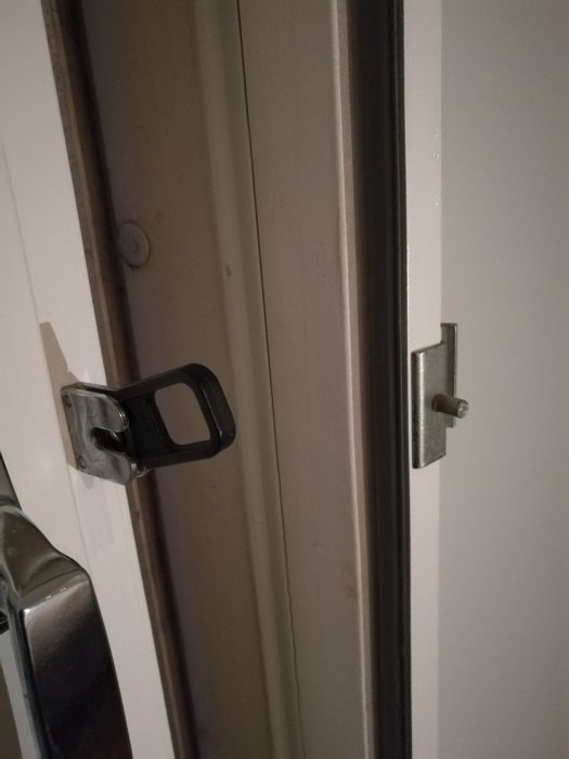 Vädringsluckans öppna beslag och saknad metallbit med pegg på en fönsterkarm.