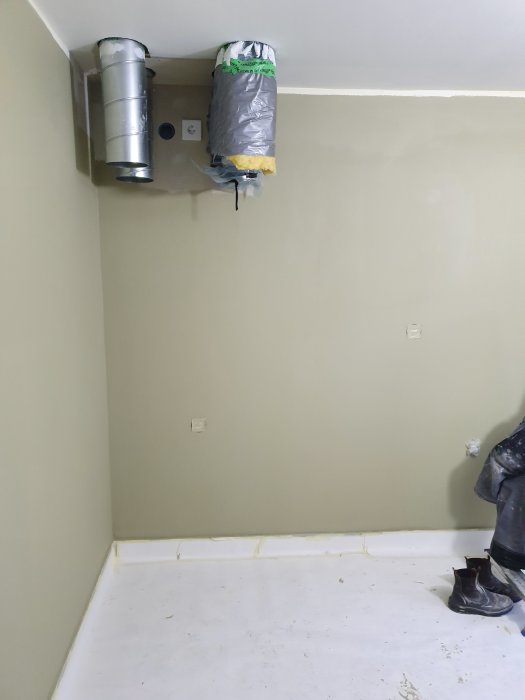 Monterat FTX-aggregat på vägg i renoverat rum med oläggat golv och väggmålning.