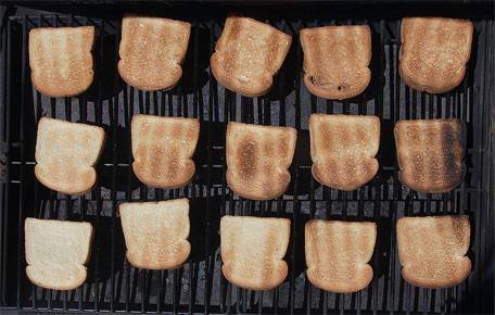 Brödskivor med olika grader av rostning på en grill.