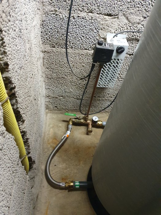 Vattenreningsutrustning med rör, filter och en hydrofor installerad i en källare med betongväggar.