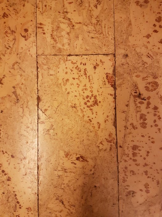 Närbild på slitet korkliknande golv med möjlig asbest, frågeställning om material och sanering.