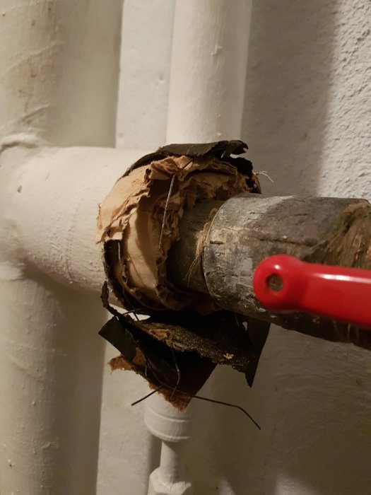 Skadad rörisolering med synlig fiberstruktur som kan innehålla asbest, i källare från 1950-talet.