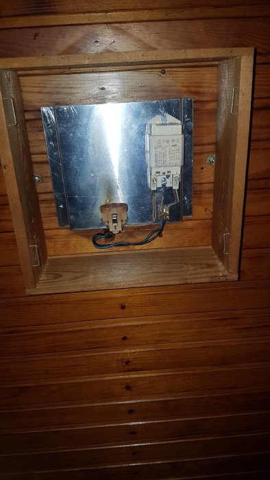 Gammal lampsockel och elanslutningar på trävägg, behöver bytas för LED-uppgradering.