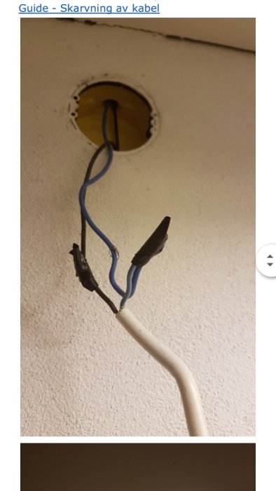 Lamputtag utan lampa med exponerade ledningar och skarvkopplingar mot en vit takyta.