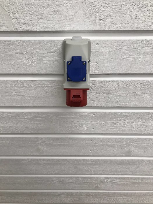 Kombo-uttag monterat på vit vägg med en röd botten och blått lock.