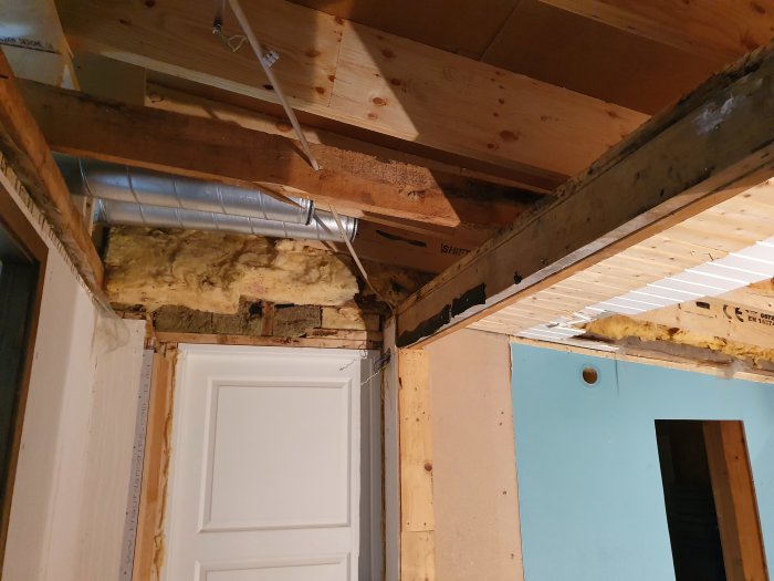 Renovering av tak med stenullsisolering kring murstock, ventilationsrör, plast och glespanel.