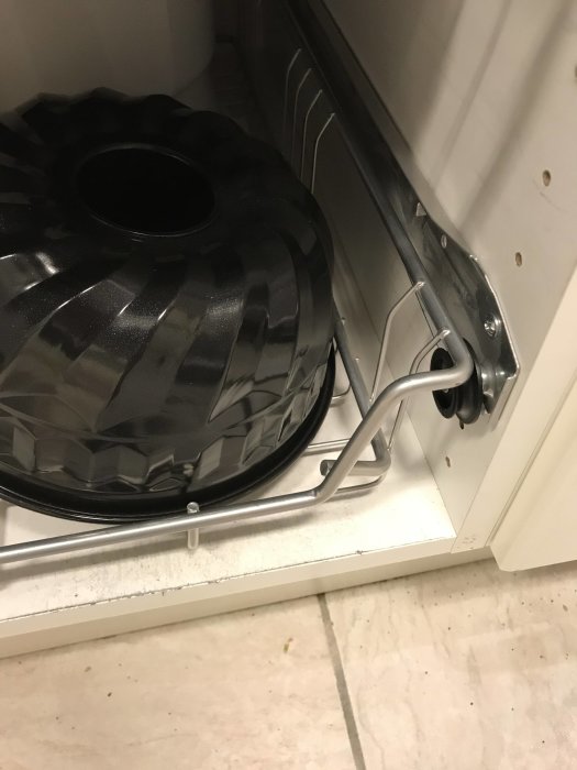 Installation av trådkorg i skåp med synlig distans och skena, inte fullt utnyttjat utrymme, och extra utrymme vid botten.