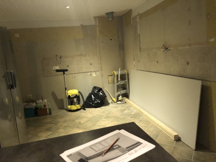 Renoveringsfas i kök med fogat golv och påbörjad garderobsinbyggnad, vägg utan köksskåp.