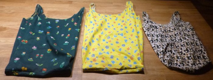 Tre hemgjorda tygkassar på golv, gjorda av färgglad återanvänd textil med olika mönster.