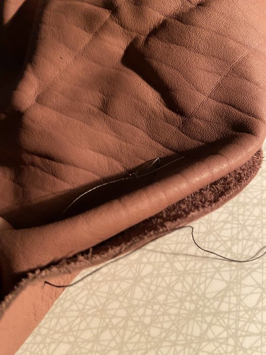 Närbild av en brun filt eller tyg med quiltat mönster och synlig söm, antyder hantverksprojekt.