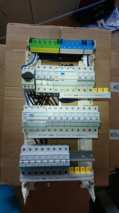 Elcentral med flera automatsäkringar och plintar på en kartong, oavslutad installation.