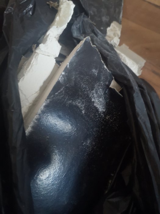 Öppnad vägg visar gipsskivor med svart baksida som kan vara ersättning för ångspärr, ingen isoleringsångspärr synlig.