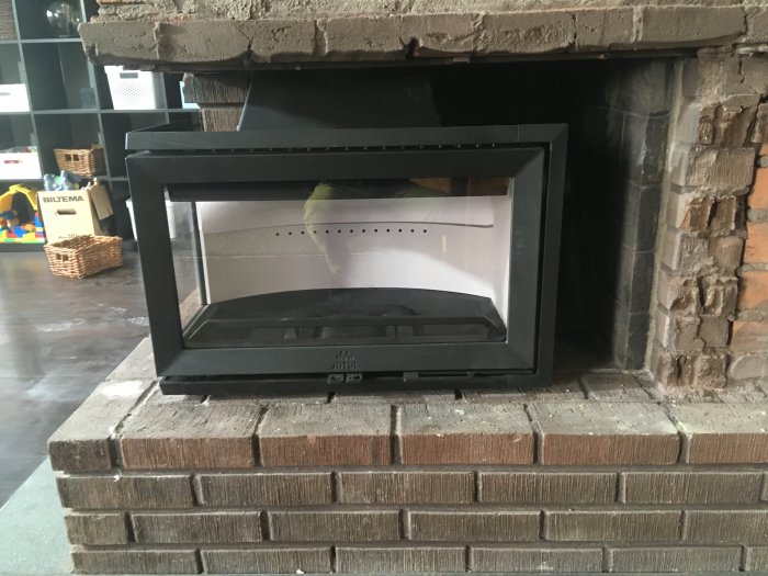 Nyinstallerad kassett i en tegelöppning för kamin med synliga murade kanter runtom.
