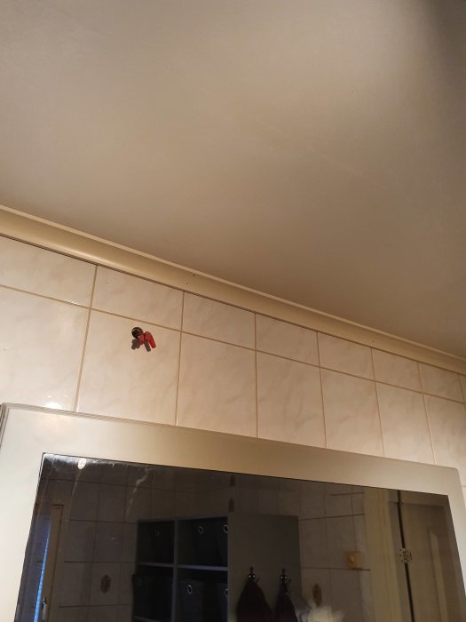 Kabel sticker ut ur väggen ovanför en badrumsspegel, ej centrerad och utan lampa.