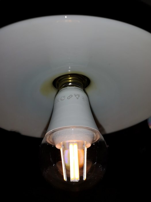 Tänd LED-lampa sedd underifrån monterad i lampsockel med vit skärm, skapar associationsleende.