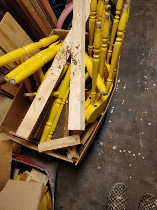 Gula svarvade träben och andra träbitar i en flyttlåda på ett verkstadsgolv, symboliserar rensning.