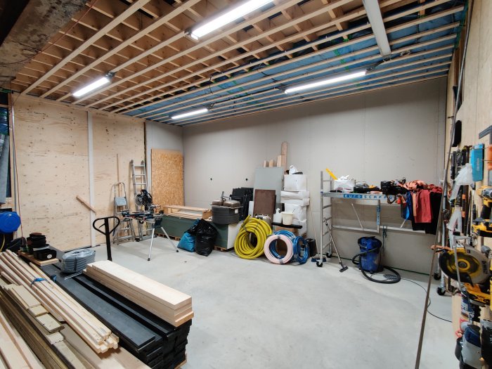 Interiör av ett garage under renovering med isolerade väggar och byggmaterial.