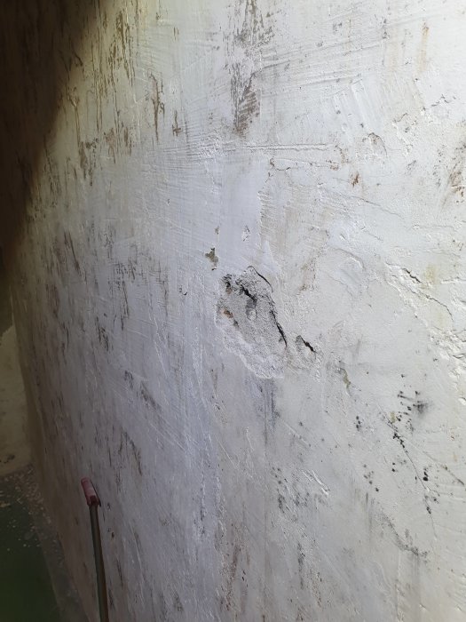 En källarvägg med tecken på fukt och svartmögel efter att en extravägg rivits bort under en renovering.