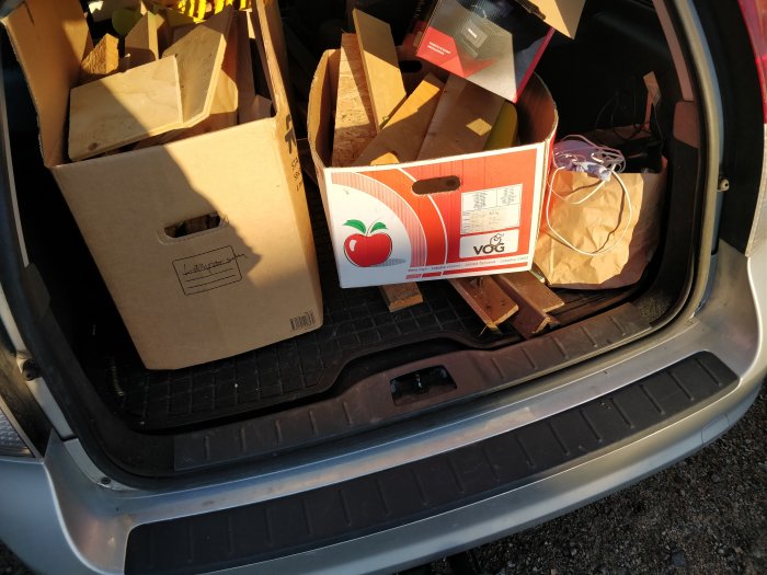 Bakluckan på en bil öppen med tre kartonger fyllda med vedklampar i för transport.
