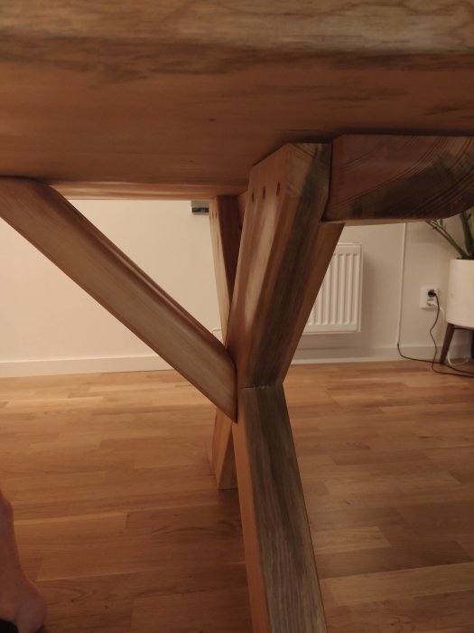 Undersidan av ett träbord där snickeridetaljer och sammankomst mellan ben och bordsskivan visas.