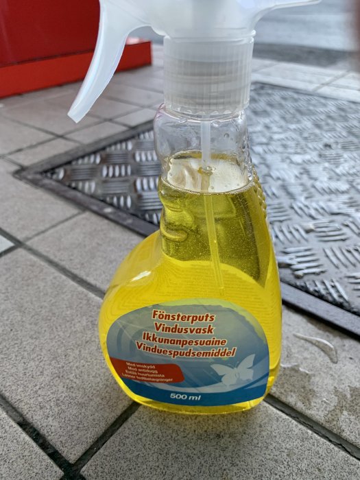 Sprayflaska med fönsterputsmedel märkt för 10 kronor på markplattor.