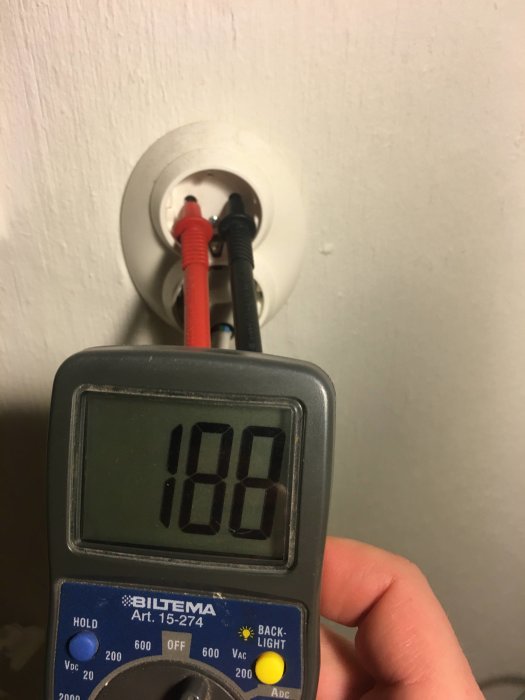 Multimeter visar 180V under mätning av ett vägguttag.