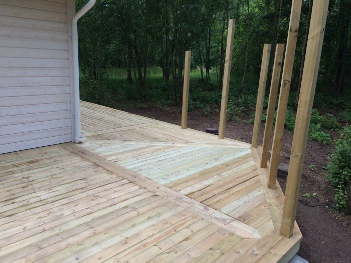 Trädäck under konstruktion med nytt virke och upprättade stolpar för framtida uterum.