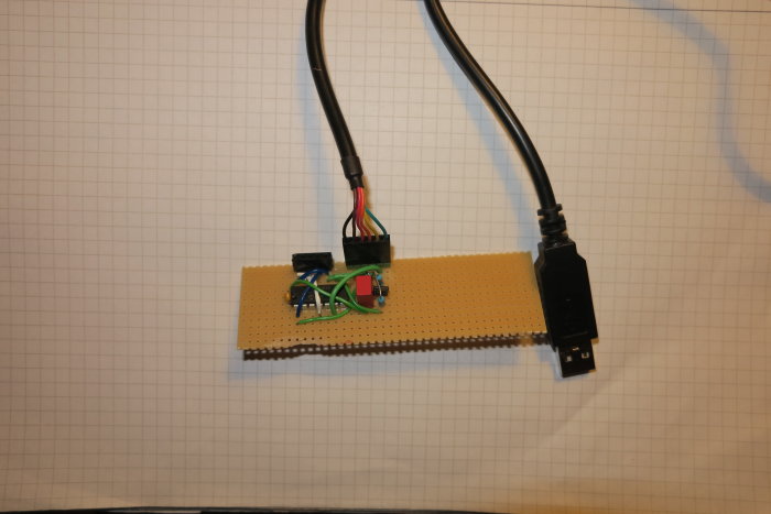 Circuit board with a PIC16F1824 microcontroller, wires, and USB port on grid paper.