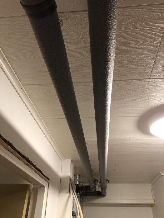 Isolerade rör i taket av ett pannrum med synlig rörkanal och Biltema rörisolering.