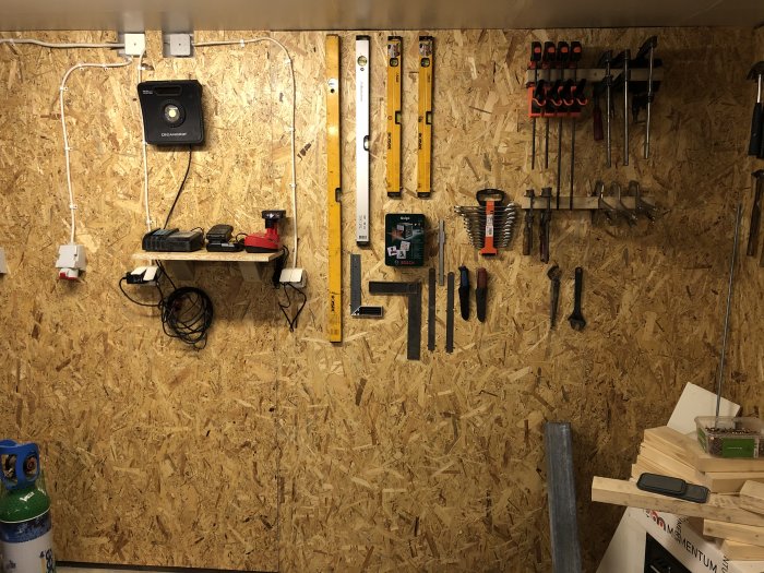 OSB-skivor på garageväggar med upphängda verktyg och en arbetsbelysning, reglar synliga bakom skivorna.