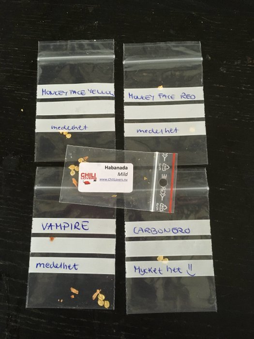 Fröpåsar med chili märkta med sortnamn som 'Monkey Face Yellow', 'Habanada' och 'Vampire'.