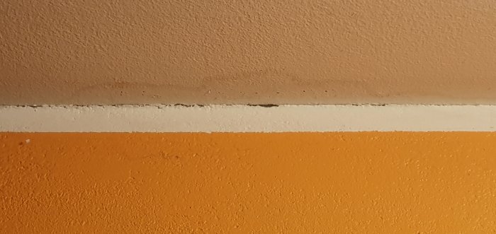 Fuktfläckar på orange vägg och vitt tak som antyder vattenskada, möjlig koppling till altanproblem.