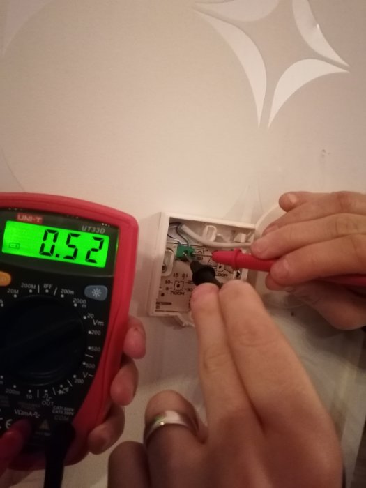 Multimeter visar 0.52 volt när den används för att mäta spänningen på en Uponor golvvärmetermostat.