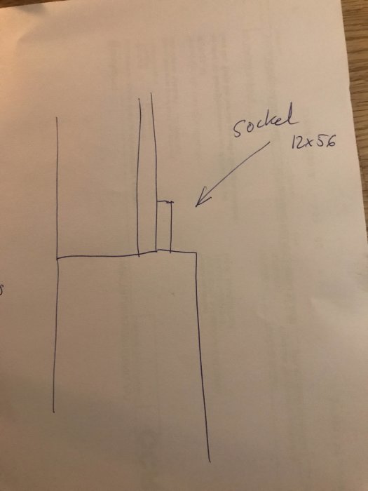 Handritad skiss av byggdetalj med måttangivelse och texten "Sockel 12x56".