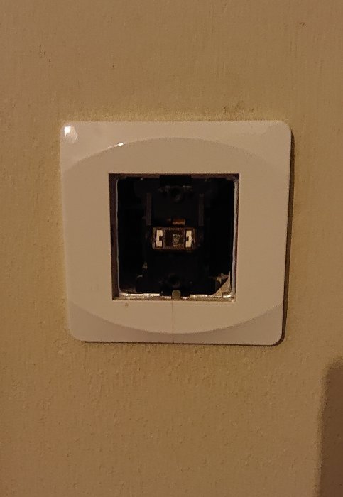Öppen eluttag utan frontpanel som avslöjar intern mekanism och ledningar, väggmonterad.