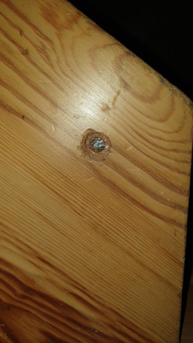 Skruv insatt i trätrappsteg utan träplugg som visar fästpunkt.