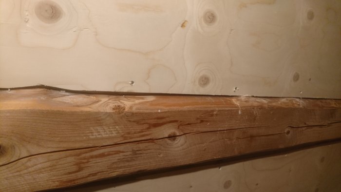 Springa mellan en trästock och plywood i ett tak, i behov av fogning.