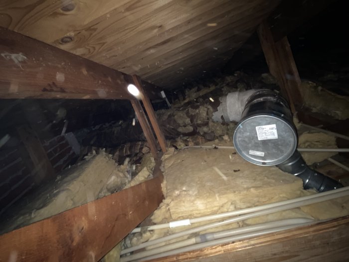 Oisolerat ventilationsrör på vinden med synliga skarvar och luckor i isoleringen.