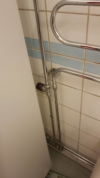 Kromad handdukstork i badrum kopplad till värmesystem, indikerar problem med uppvärmningen.
