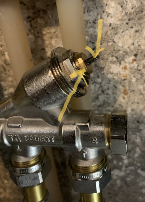 Mässingsventil med markerad ventilkägla och justerbar del, omringad av rör och fästelement.