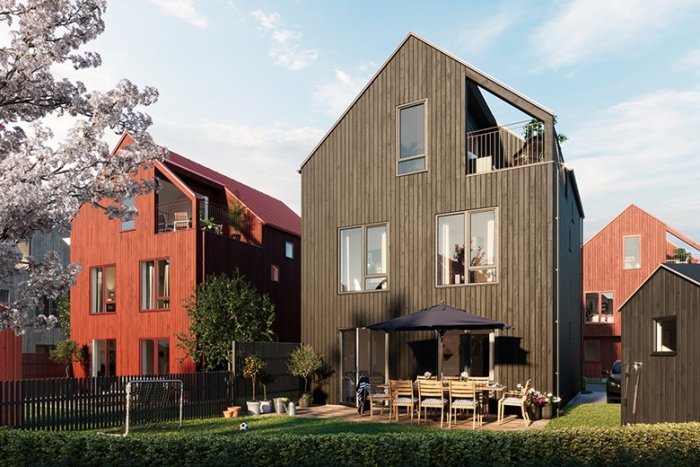 Moderna radhus i olika färger med trädgård och balkong i ett bostadsområde.