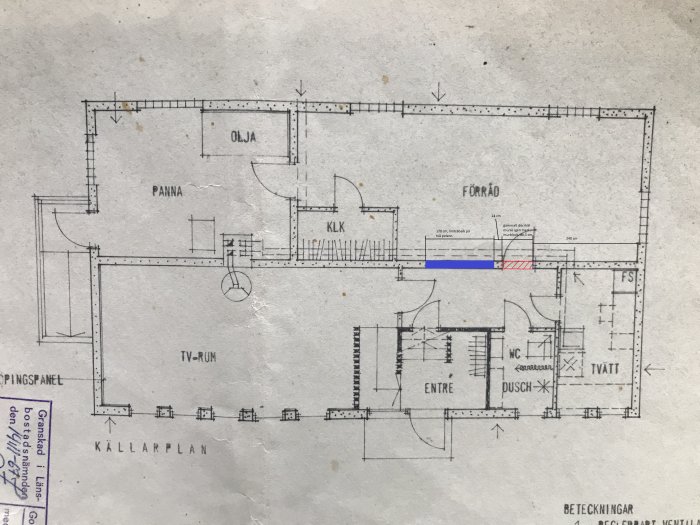 Ritning av källarplan med markerat befintligt dörrhål i rött och planerat nytt dörrhål i blått.