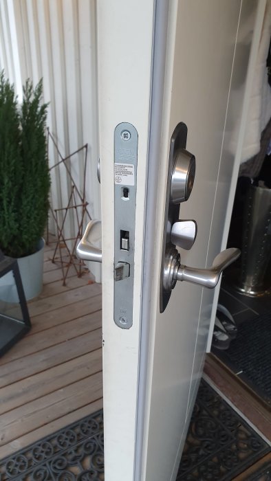 Vit dörr med Assa låskista och silverfärgade handtag som krånglar, indikerande slitage.
