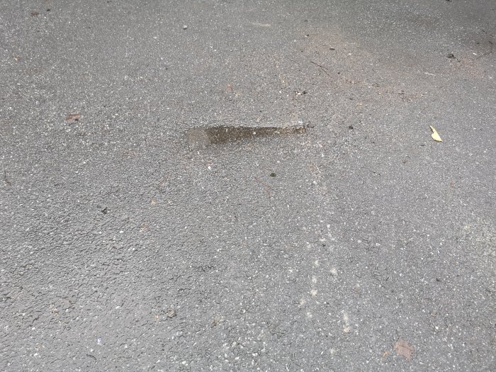 Försänkningar och skador på asfaltsyta där en tung container dragits.