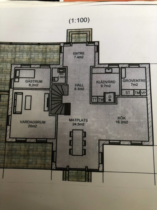 Ritning av ett förslag på husplan med betecknade rum som entre, vardagsrum, gästrum och kök, i skala 1:100.