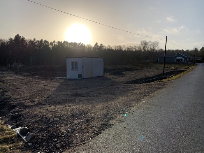 Nyplanerat område med grovt grus mellan infarter vid solnedgång.