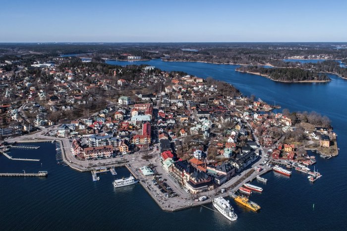 Flygbild över Vaxholms stad med båtar, byggnader och omgivande vatten.