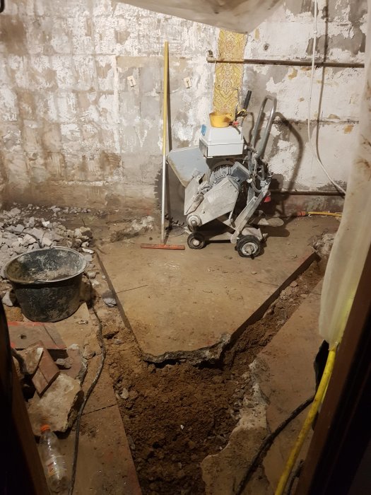 Renoveringsarbete i badrum med urrivet golv och väggar, byggmaterial och verktyg synliga.
