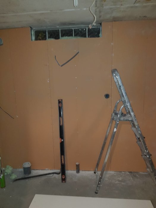 Badrum under renovering med gipsväggar, stegar och installationsrör.