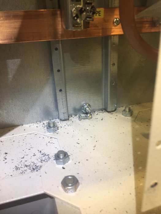 Elektrisk installation med kopparledare, skruvar och utbrytningar på ett skyddande plastomslag.